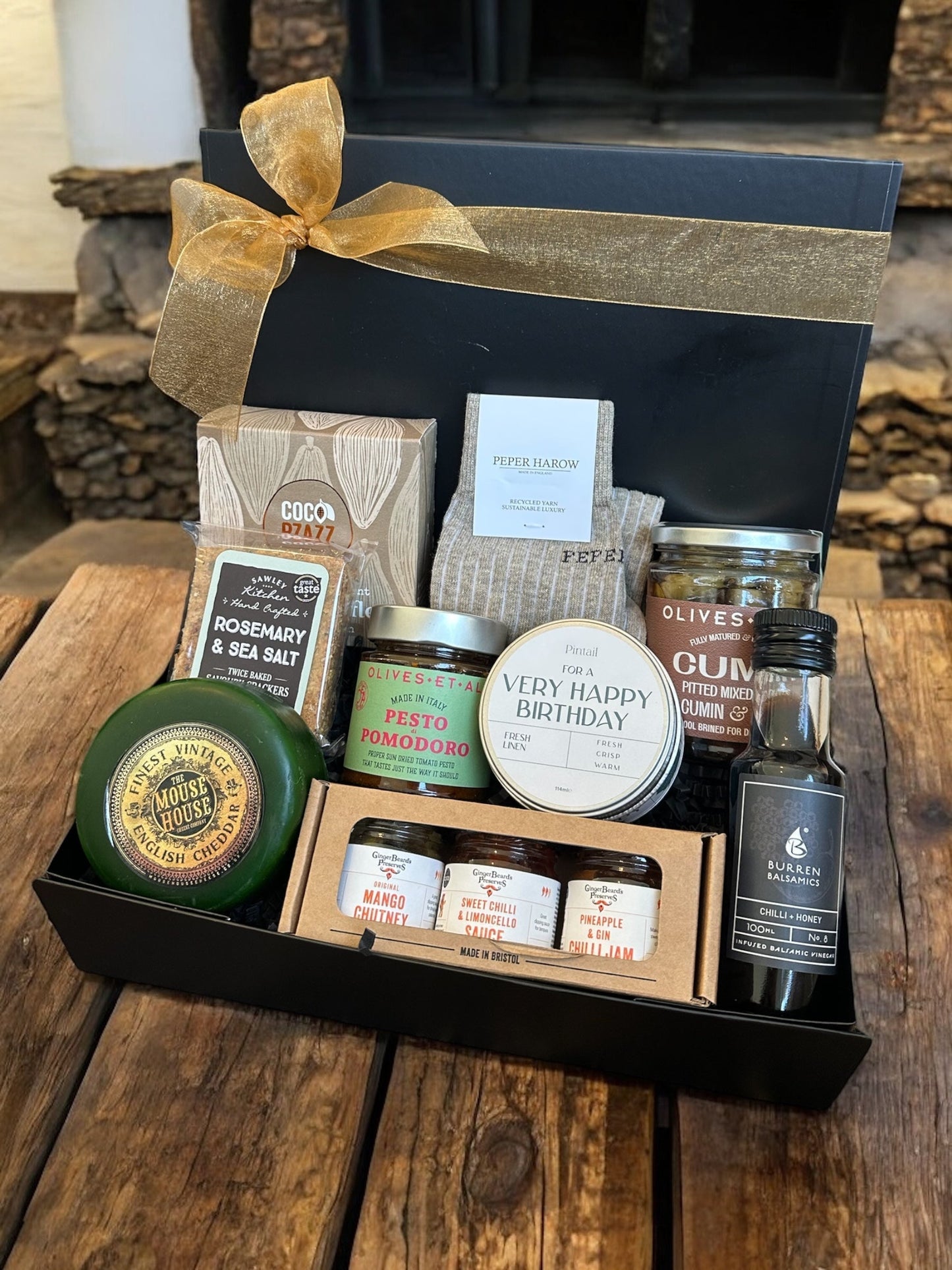 Gourmet Happy Birthday gift box with vintage cheddar, crackers, preserves, sun dried tomato pesto, balsamic vinegar, olives, linen candle, and Peper Harow socks.