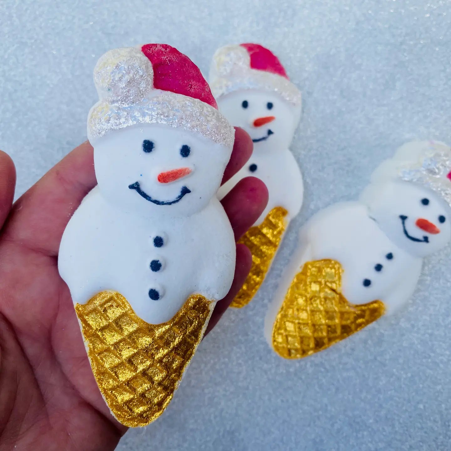 Snow Cone bath bomb with hand-painted Santa design and gold mica cone, wrapped in eco-friendly film.