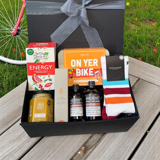 Cycling essentials gift box with energy tea, ginger boost honey, neroli hand cream, joint ease oil, serum, and sports socks