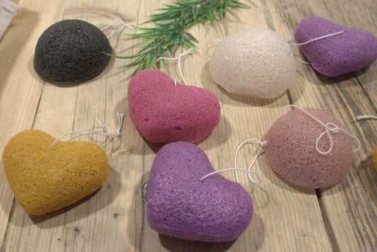 Soft and natural Konjac heart rose sponges in various colors on a wooden surface.