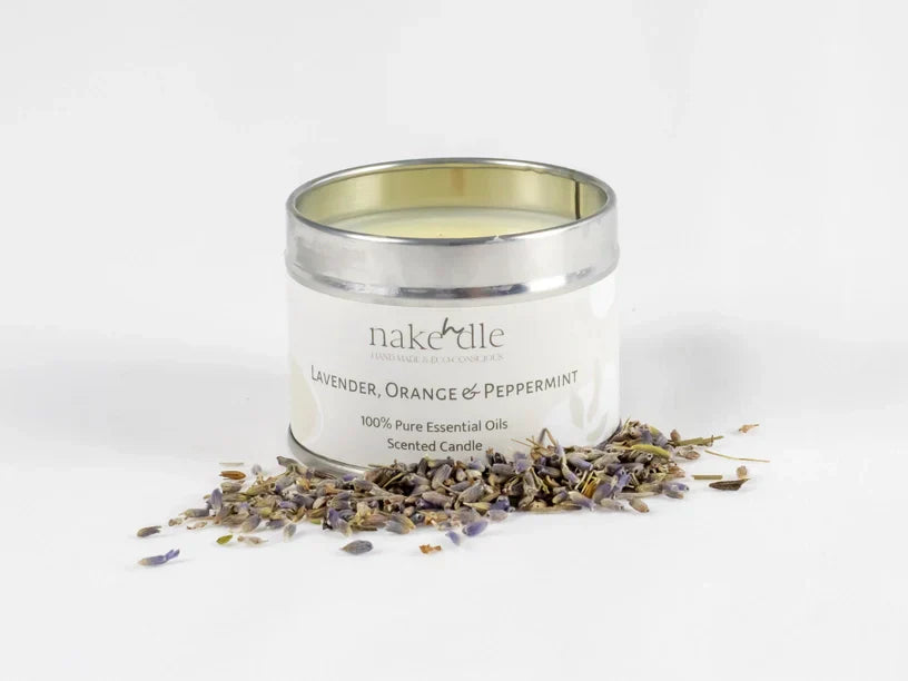 Lavender, orange, and peppermint essential oil candle in tin surrounded by dried lavender flowers.