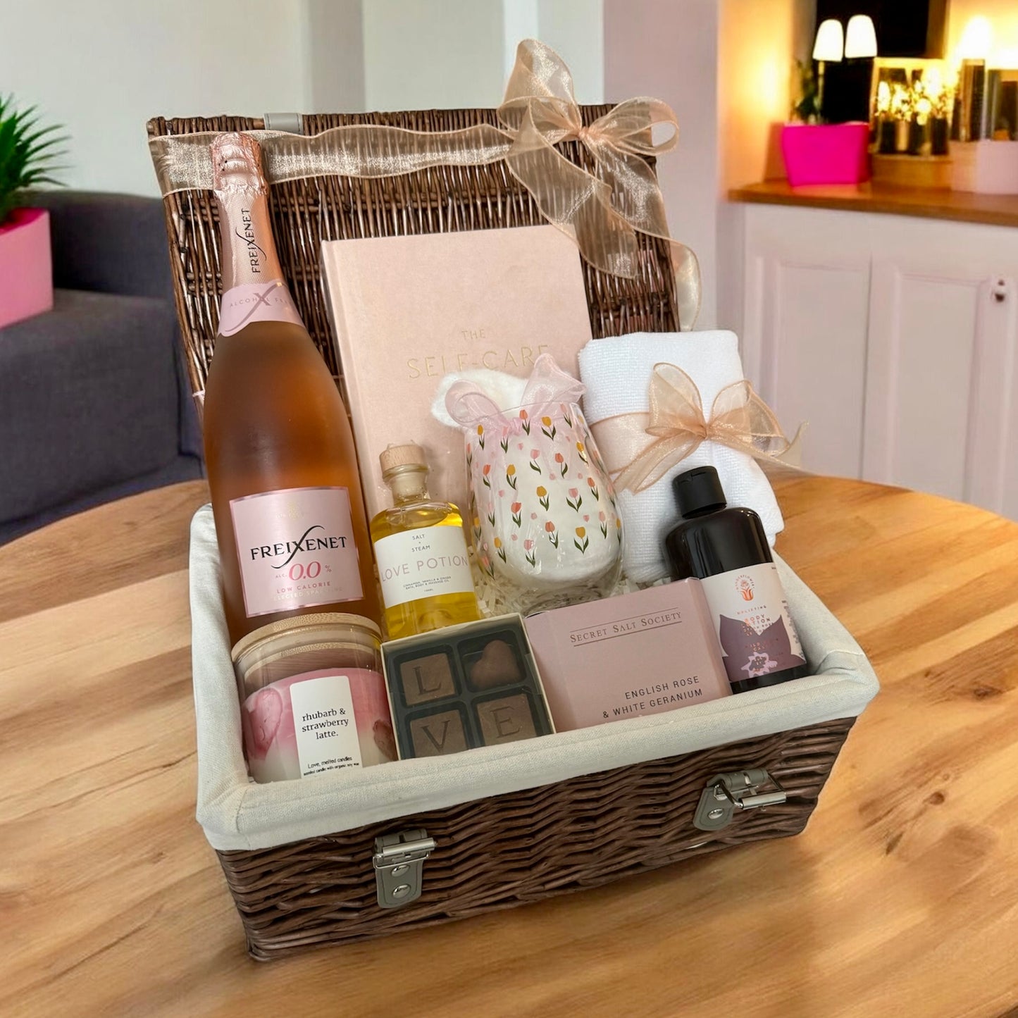 Gift basket with wine, snacks, and other items on a wooden table.