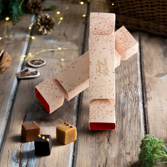Luxury Fudge Christmas Crackers in festive indigo and buff designs, each filled with handmade fudge squares in Sea Salted Caramel, Chocolate Orange, and Speculoos.