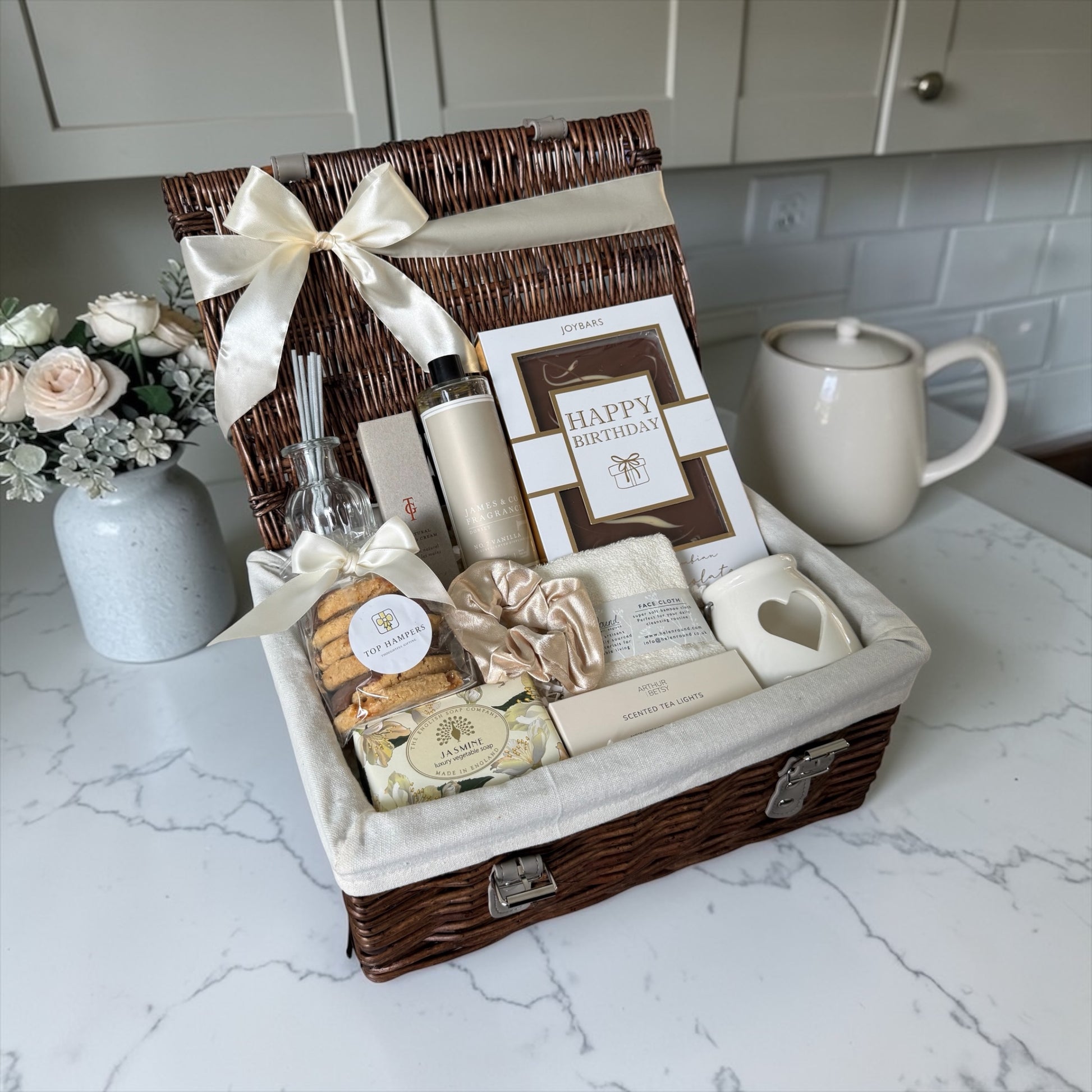 Luxury birthday gift hamper for her with chocolate, biscuits, hand cream, diffuser refill, tea light holder and pamper items.