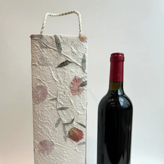 Pretty floral mulberry paper wine gift bag with elegant flower design next to a wine bottle.