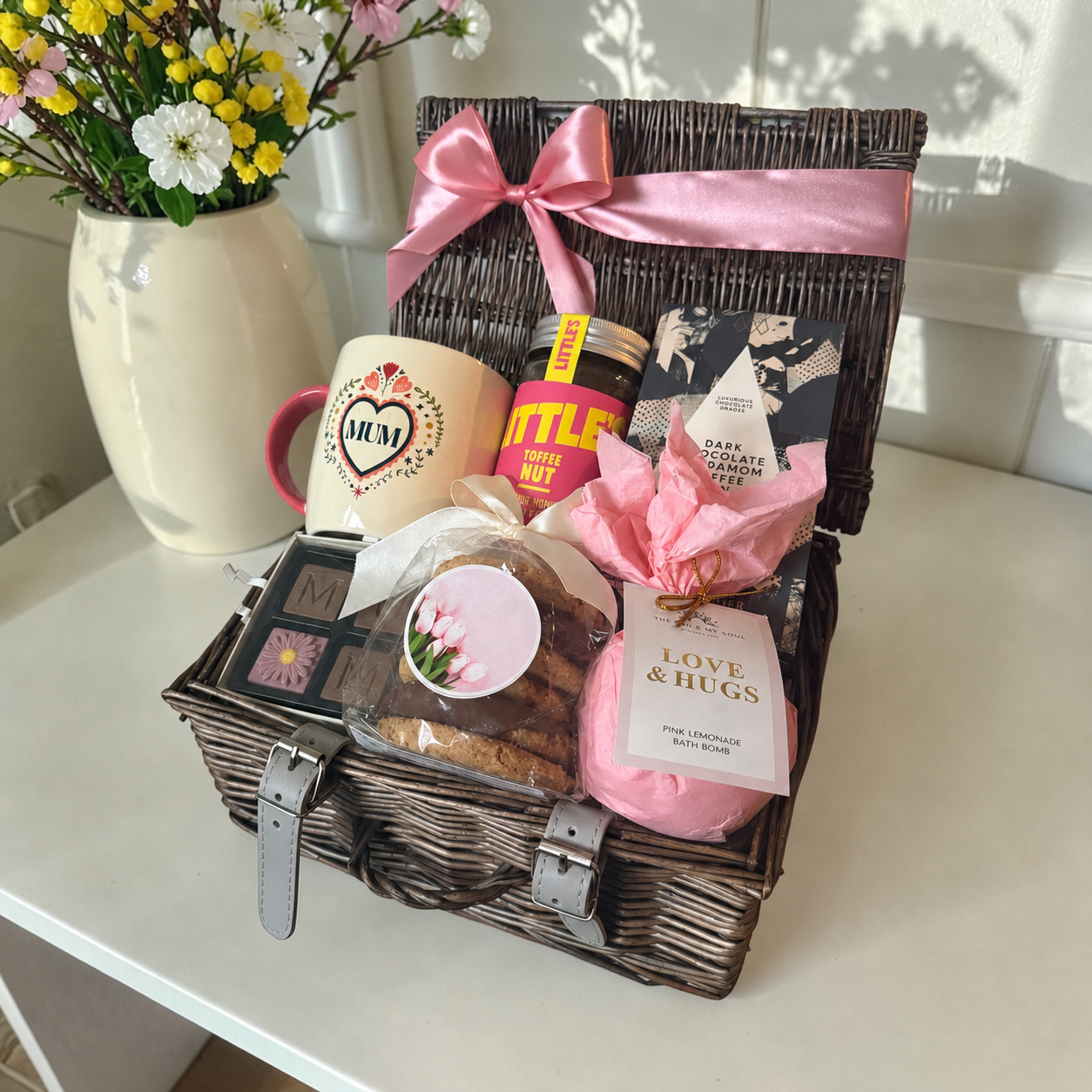 Gift basket with a mug, cookies, and other items on a table.