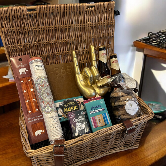 Hamper filled with music-themed gifts for a music lover, featuring a gold hand gesture ornament, records, incense sticks, and notebooks.
