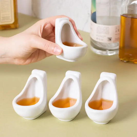 Urinal shaped shot glasses set of four on a countertop.