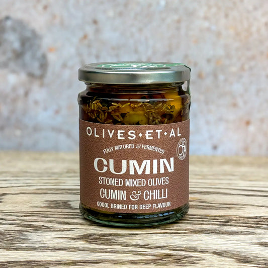 Olives Et Al Cumin Mint Chilli Pitted Mixed Olives jar on wooden surface.