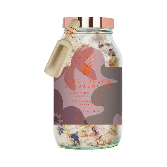 Wanderflower Patchouli & Sandalwood Bath Salts in elegant packaging, displayed beside a bath setup with candles and natural accessories.