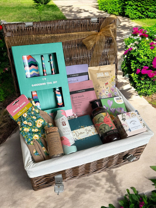 Queen Bee Gardening Hamper with colorful tools, floral gloves, masks, candle, seed bombs, and bee-themed notebooks.