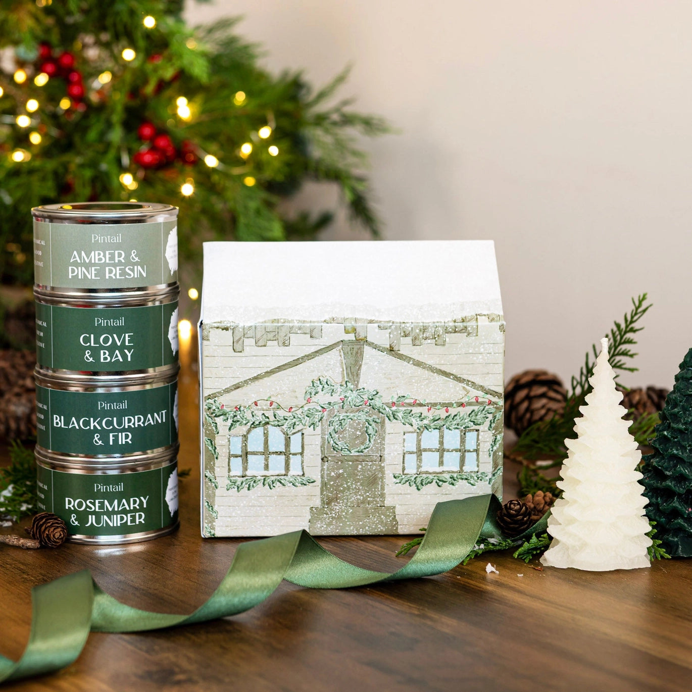 Pintail Santa’s Workshop Gift Set in a festive cardboard house with four paint pot candles in Amber & Pine Resin, Clove & Bay, Blackcurrant & Fir, and Rosemary & Juniper scents.