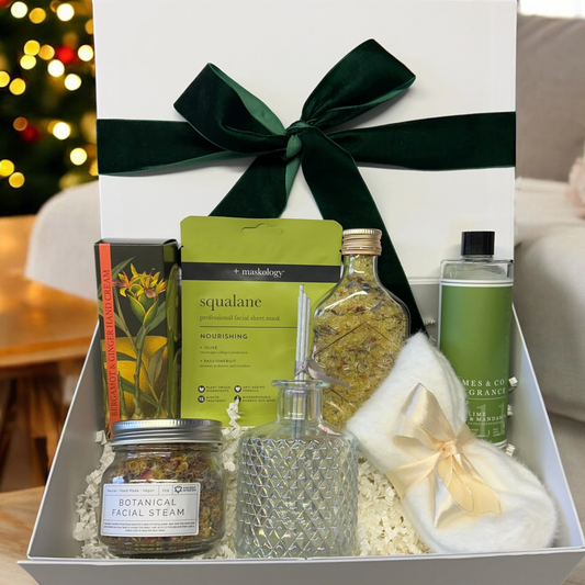 Self Care Box with hand cream, diffuser, bath salts, socks, facial steam, and sheet mask.