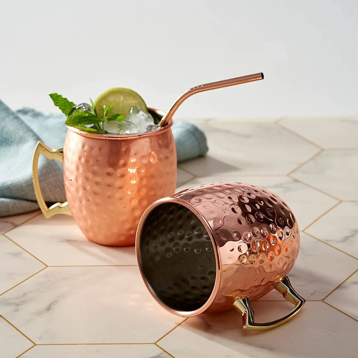 Set of four Moscow Mule cocktail mugs made from copper and stainless steel on a marble surface.
