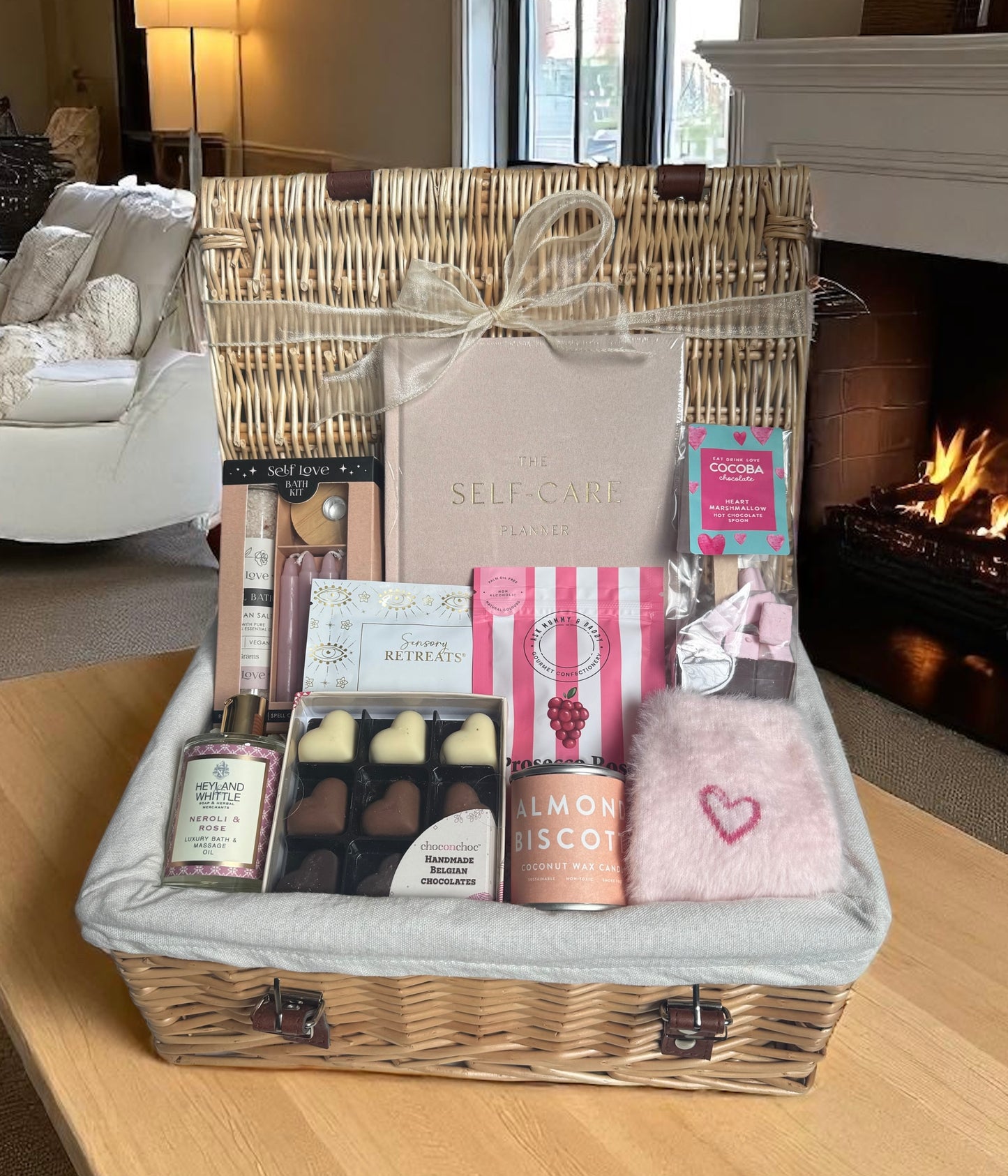 Pampering gift box with chocolates, self-care items, and Prosecco rosé gummies in a woven basket.