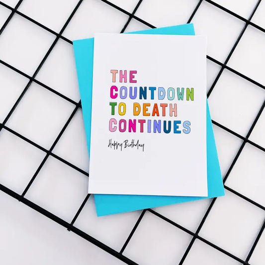 Humorous "The Countdown to Death Continues" birthday card on recycled white board with colorful text.