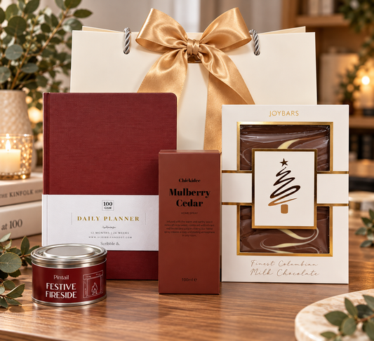 Fireside Focus Christmas Gift Bag with burgundy daily planner, Mulberry Cedar home spray, Festive Fireside candle and Joybars milk chocolate, finished with a gold bow.