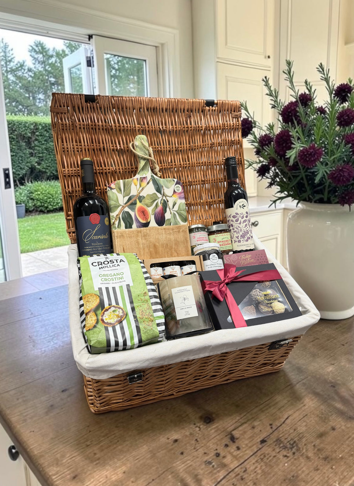 The Gourmet Delights Hamper with a fig print board, chutneys, fudge and a choice of red wine, Champagne, or no alcohol. A generous foodie gift.