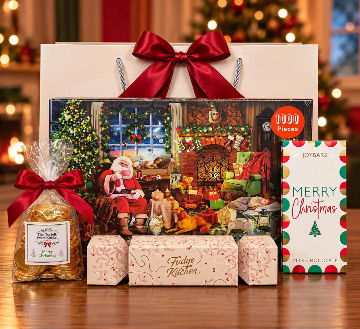 The Night Before Christmas Gift Bag on a wooden table, with a 1000 piece jigsaw puzzle of Santa by the fireside, a Joybars Merry Christmas milk chocolate bar, a Fudge Kitchen fudge cracker and a bag of gold chocolate coins, in front of a white gift bag tied with a satin ribbon.