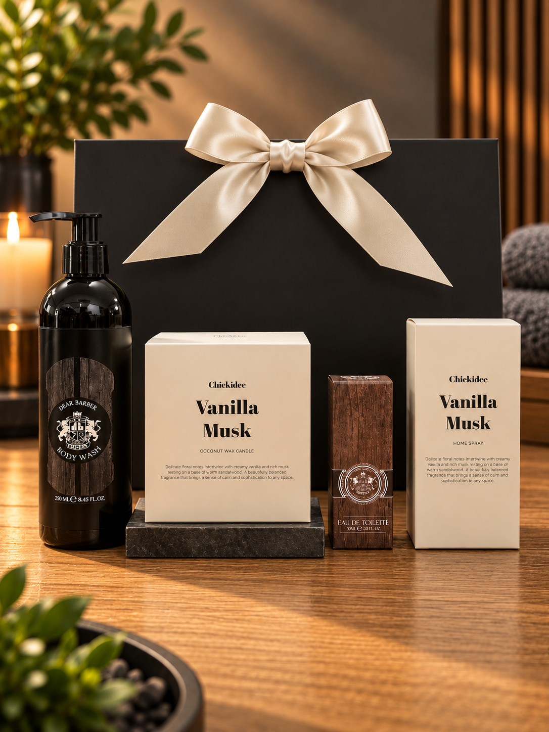 The Vanilla Musk Grooming Gift Bag on a wooden table, with a bottle of Dear Barber body wash, a Chickidee Vanilla Musk coconut wax candle, a boxed 30ml Dear Barber eau de toilette and a Chickidee Vanilla Musk home spray, in front of a black gift bag tied with a cream satin ribbon.