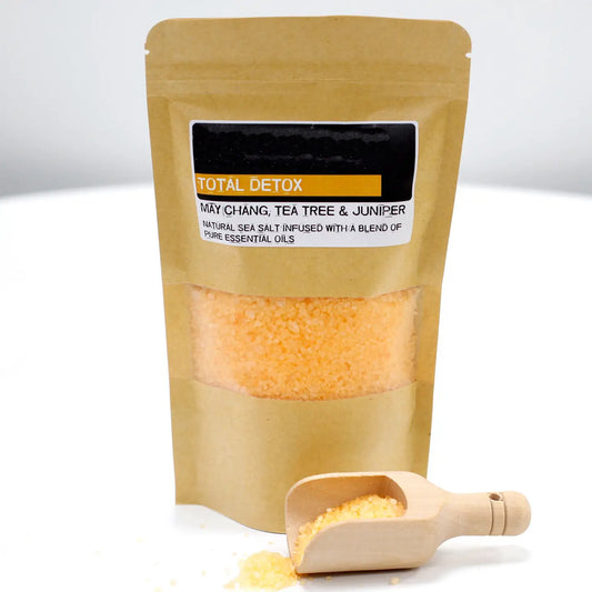 Total detox bath salts with essential oils in a brown bag and wooden scoop.
