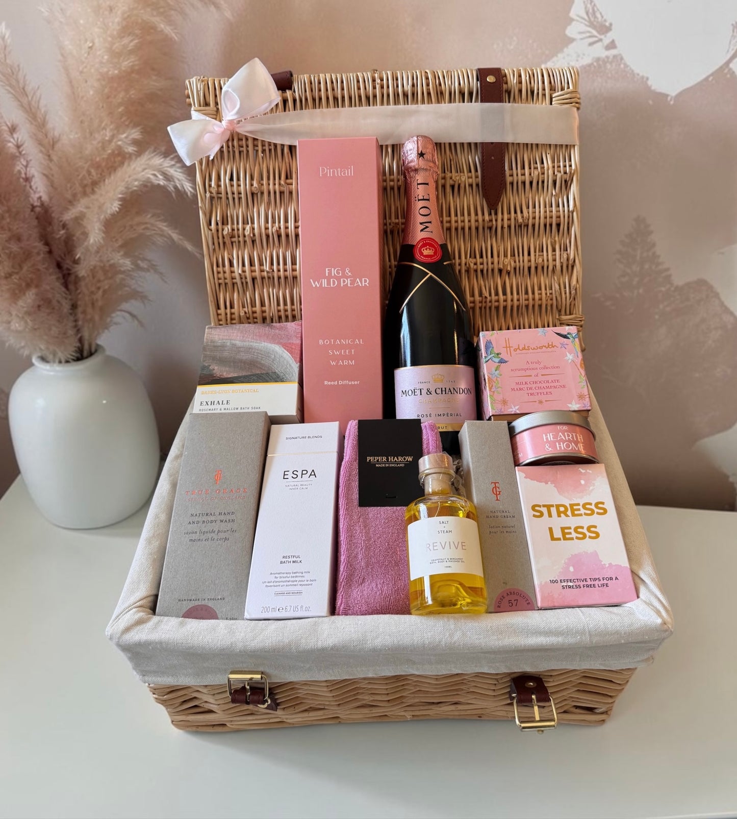 Gift basket with a bottle of champagne, skincare products, and other items on a white surface.