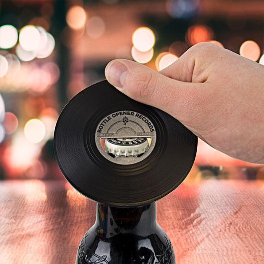 Vinyl record-shaped bottle opener held above a beer bottle.
