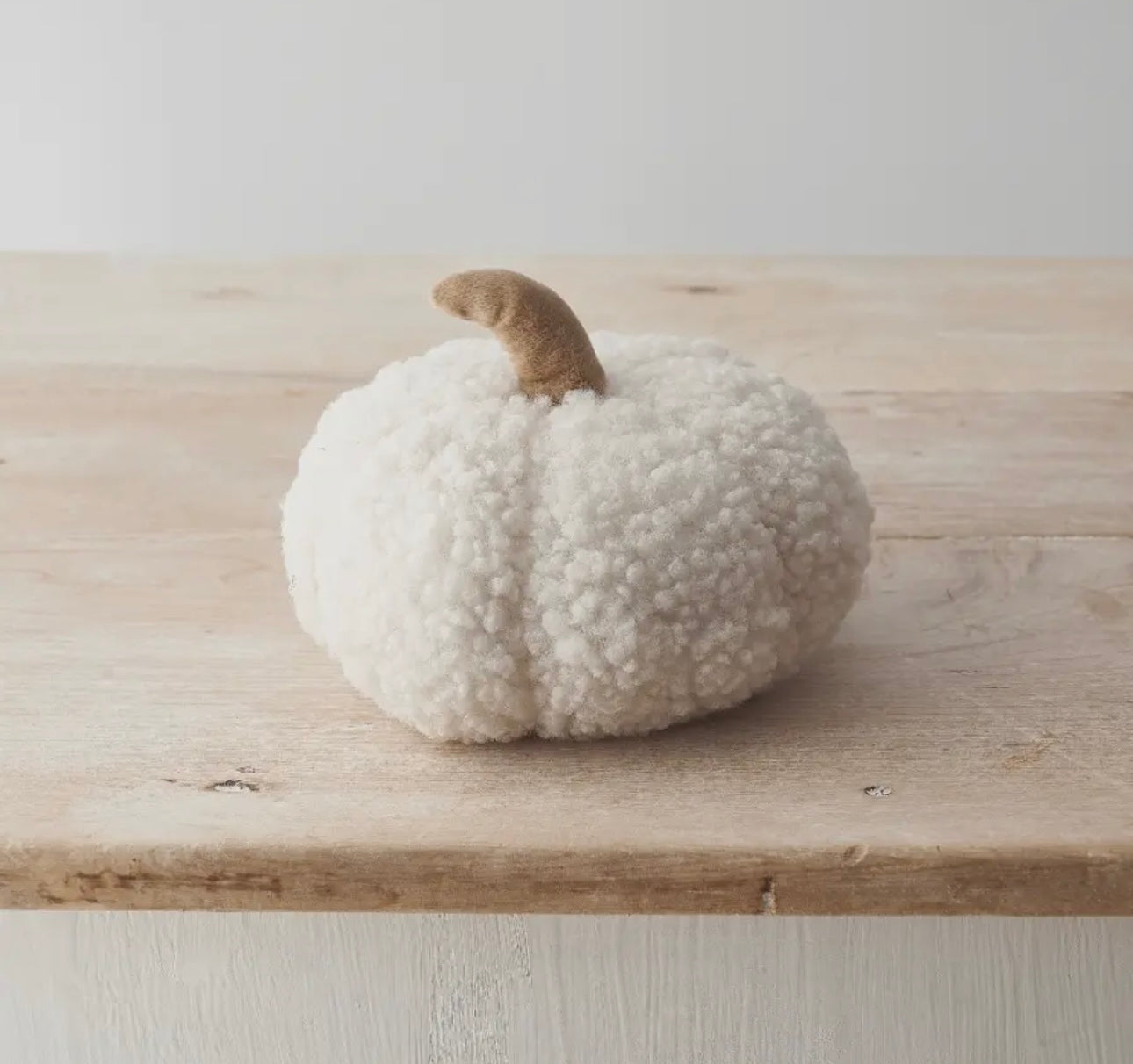 White textured pumpkin on a wooden surface with a light background