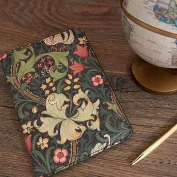 William Morris floral passport case with iconic botanical print on wooden table next to a globe and pen.