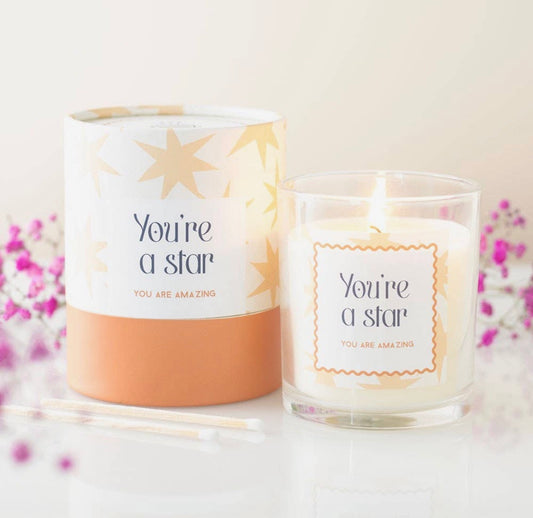 Candle with 'You're a star' message and packaging on a light background