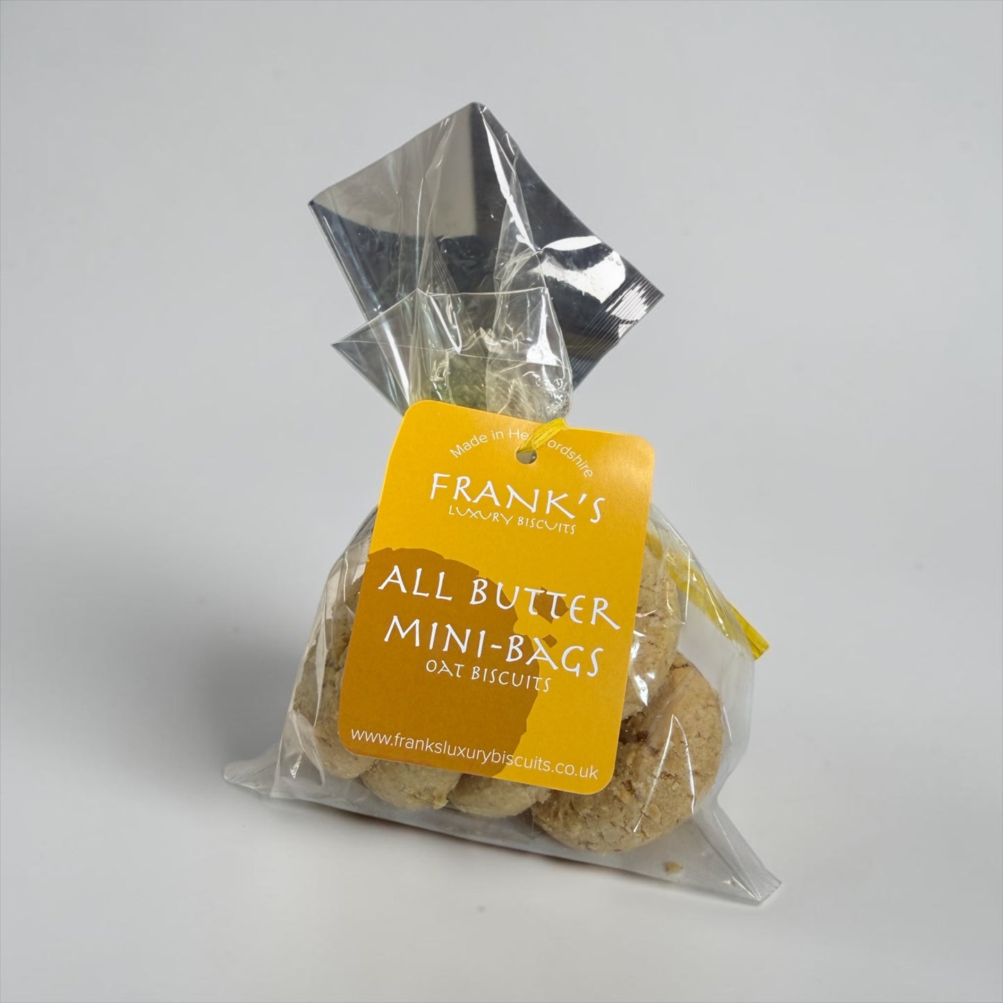 Packaged mini-bags of oat biscuits with a yellow label on a gray background