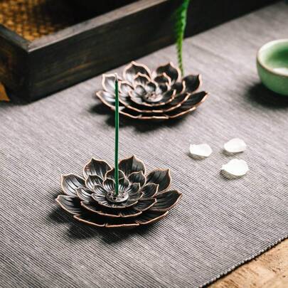 Black lotus incense holder in Zen style on a mat surface.
