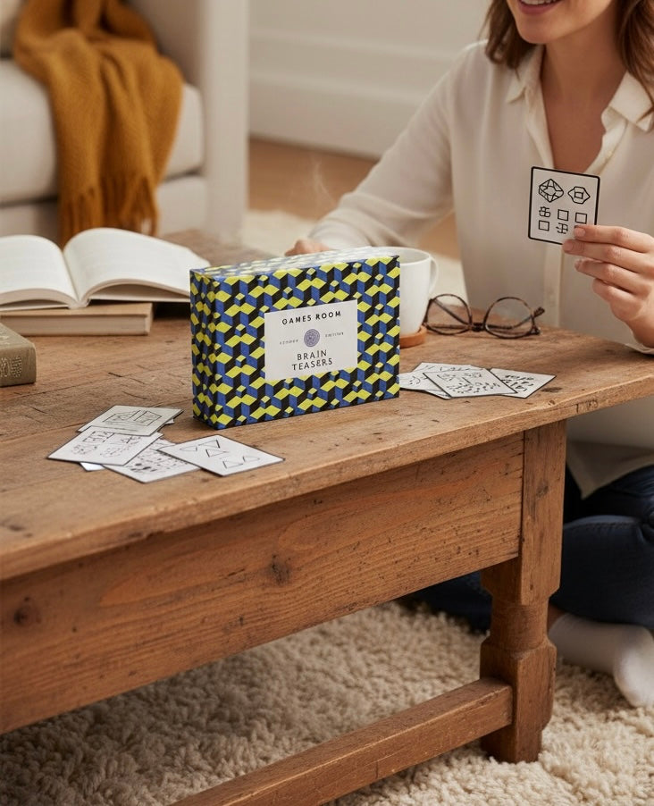 Person playing a card game at a wooden table with a box labeled 'Games Room' in the background.