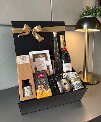 Premium congratulations gift hamper with chocolate, notebook, reed diffuser, gourmet cheese bites, rhubarb vodka liqueur and champagne.