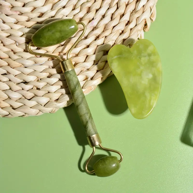 Jade roller and gua sha set in green with pink handle and gold accents for facial massage.