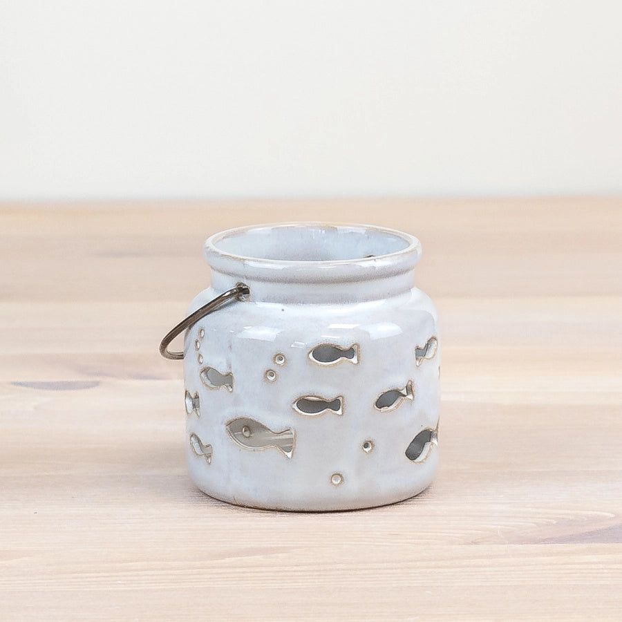 Ceramic jar with fish designs on a wooden surface