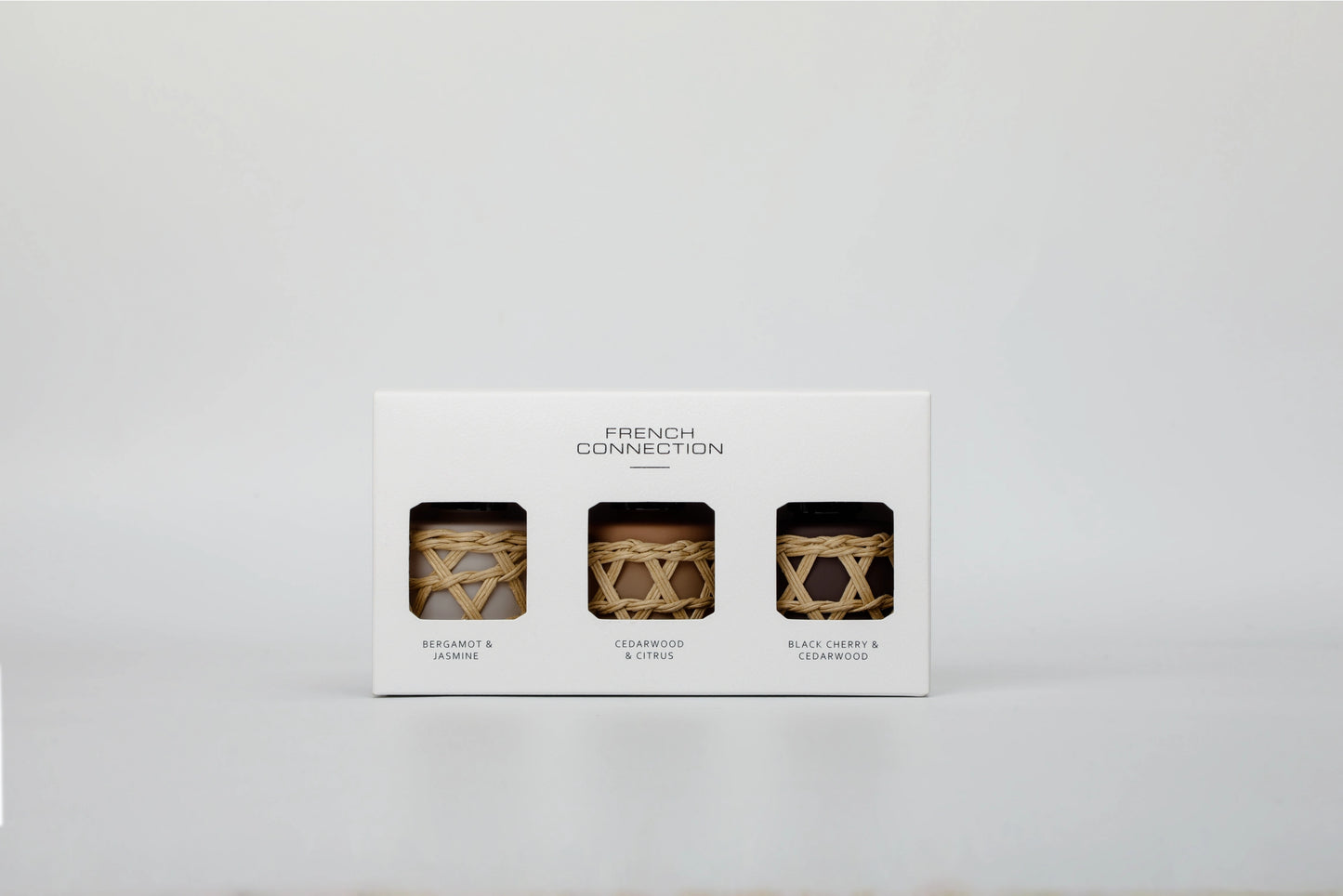 Three candles in decorative holders on a white box labeled 'French Connection' against a light gray background.