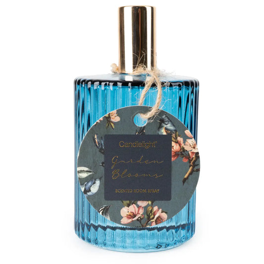 Blue room spray bottle with gold cap and floral tag labeled "Garden Blooms".