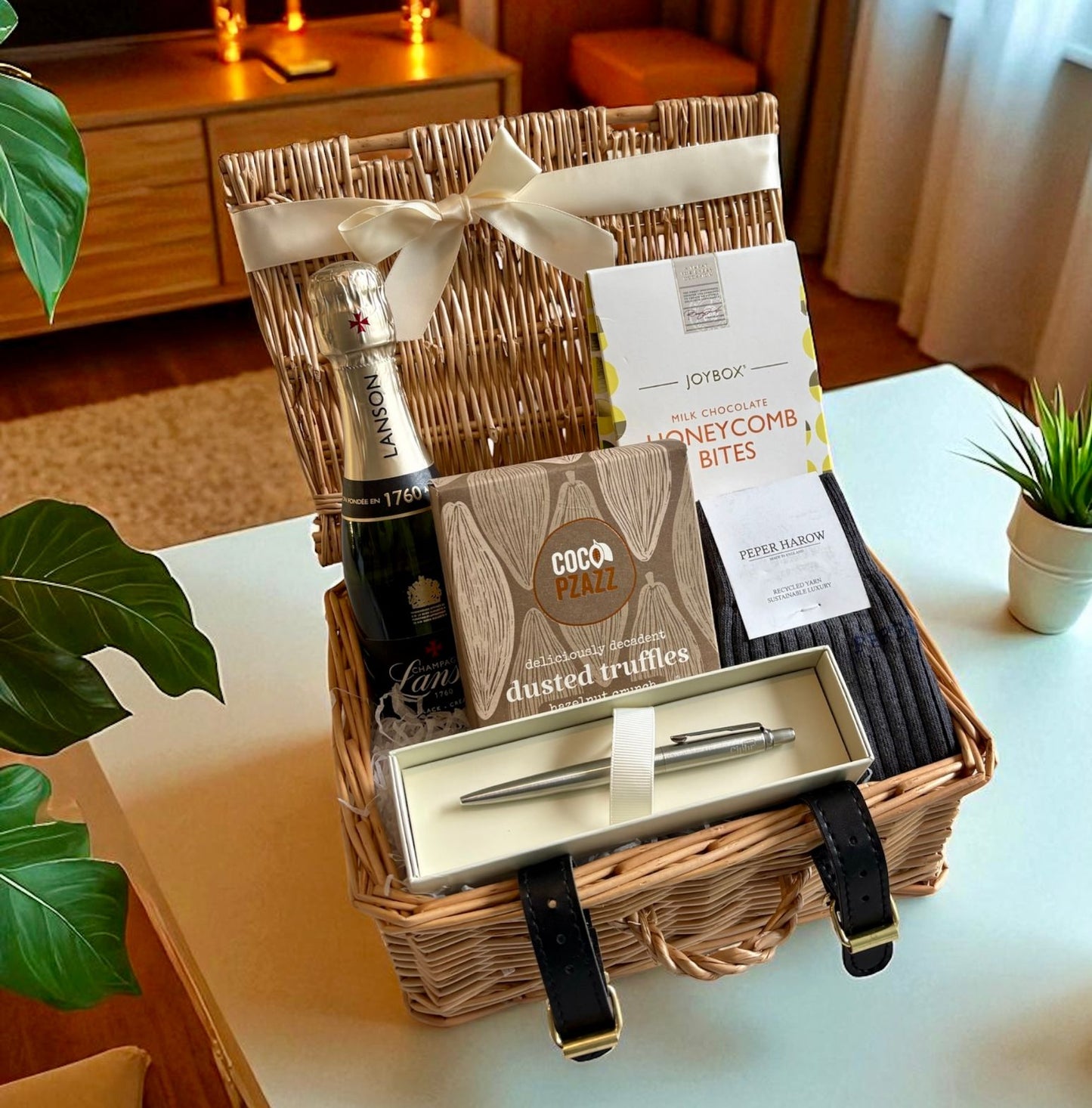 Gift basket with wine, truffles, and a pen on a table.