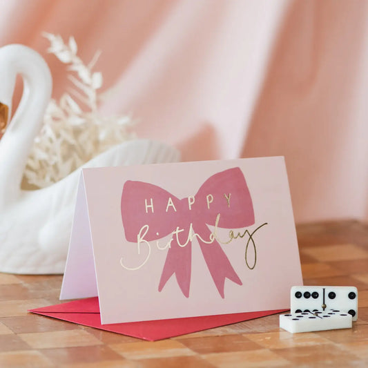Happy Birthday card with gold foil and pink bow design.