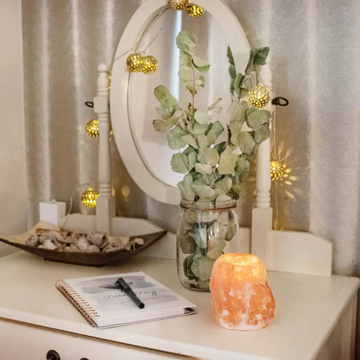 Himalayan salt candle holder emitting warm glow on a decorated table.