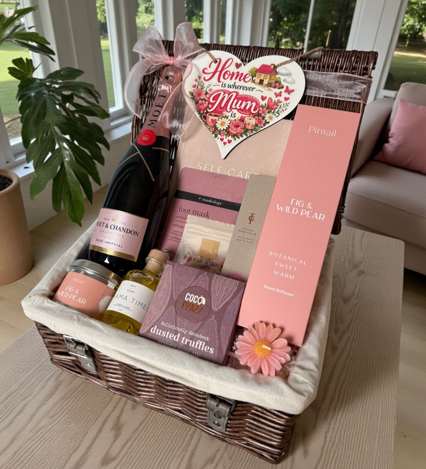 Luxury gift hamper for Mum with champagne, self-care treats, chocolates and floral diffuser in a wicker basket.