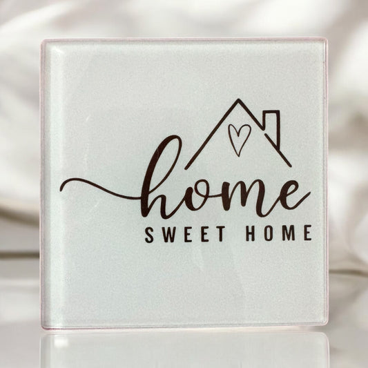 Decorative tile with 'home sweet home' text and mountain design on a white background