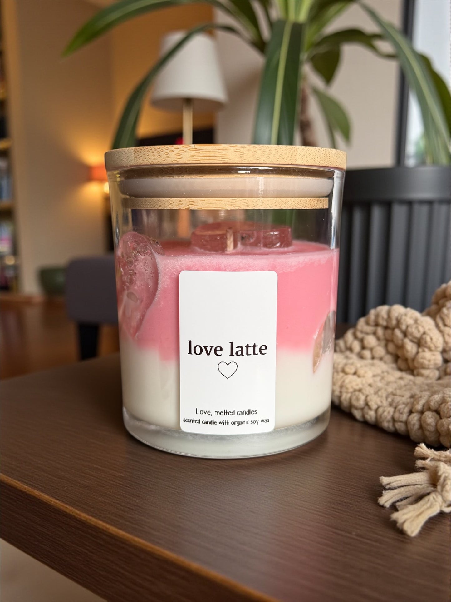 Candle labeled 'love latte' on a wooden surface with a blurred indoor background