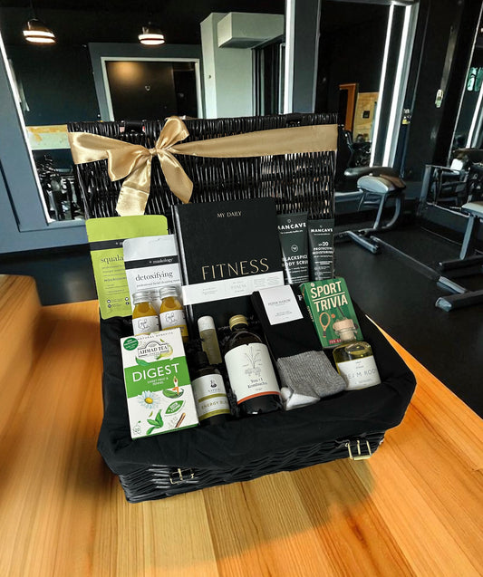 Gift basket with health and fitness products on a wooden table in a gym setting, male fitness gift hamper. 