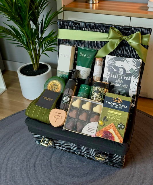 Gift basket with various items including chocolates and snacks on a wooden surface.