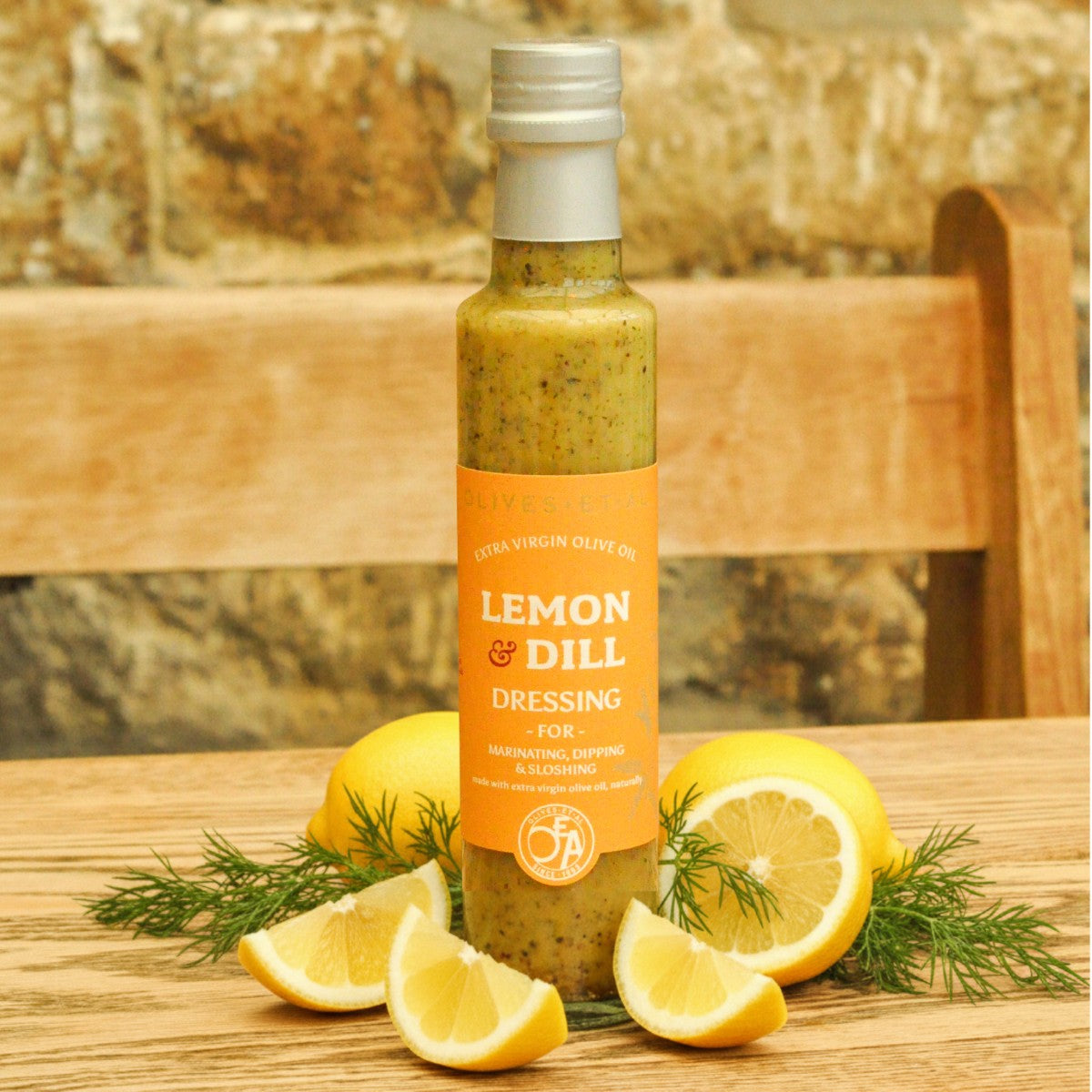 Bottle of Lemon & Dill dressing with lemons and dill on a wooden surface