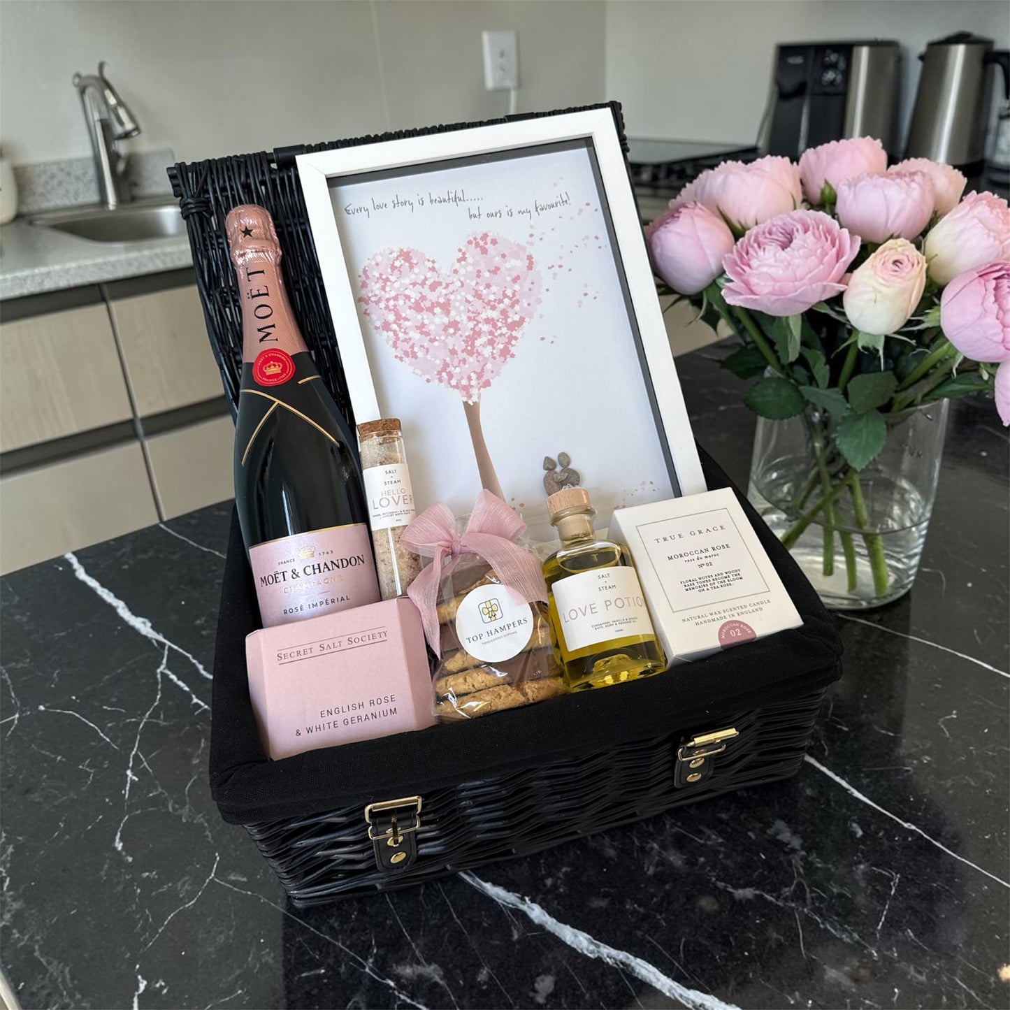 Romantic gift hamper with Moët & Chandon Rosé, rose candle, bath products, chocolates and love-themed framed artwork.