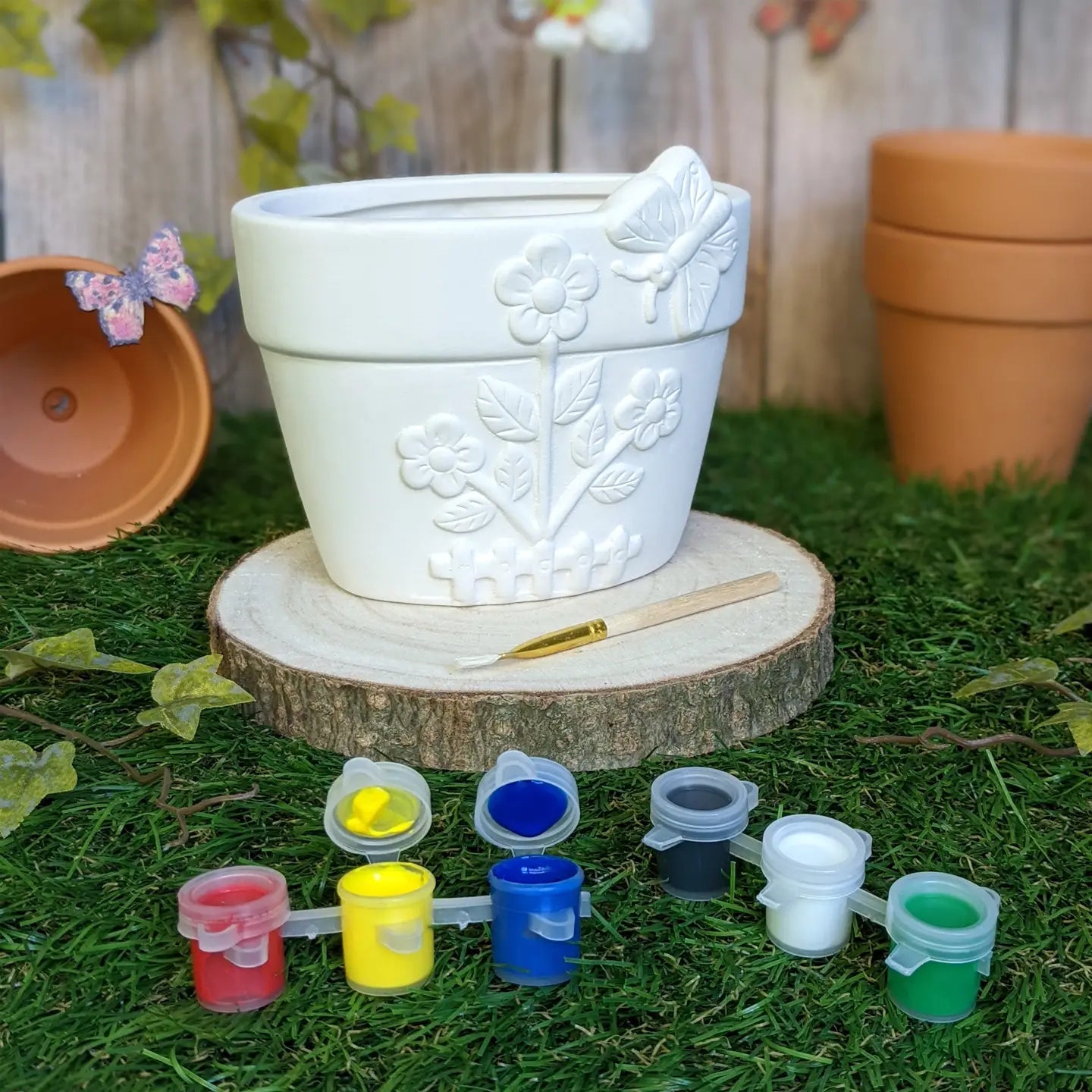 Ceramic flower pot with floral design, paint set, and brush for DIY painting.