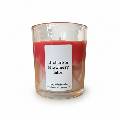 Candle with a label reading 'rhubarb & strawberry latte' on a white background